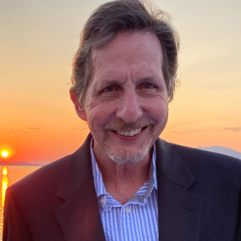 A man in a suit and tie smiling for the camera.