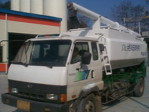 A white truck with a man on the back of it.