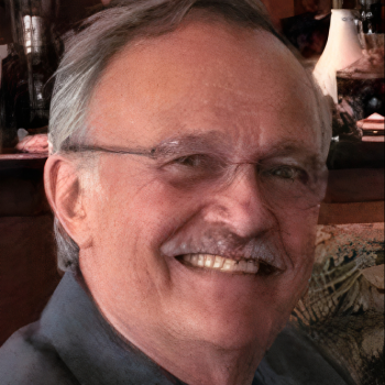 A man with glasses smiling for the camera.