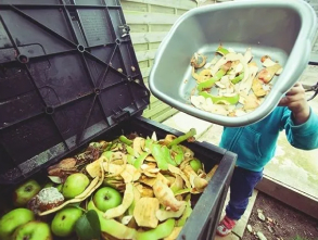 A person holding a trash can and some food