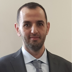 A man in suit and tie standing next to wall.